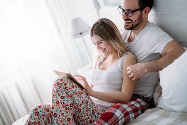 Genç mutlu çift yatak odasında dijital tablet kullanma