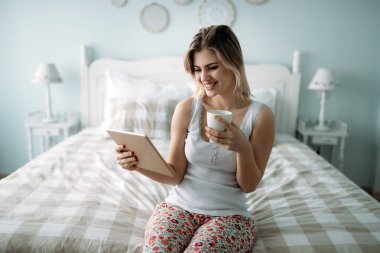 Genç güzel kadın yatak odasında dijital tablet kullanma