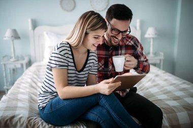 Genç mutlu çift yatak odasında dijital tablet kullanma