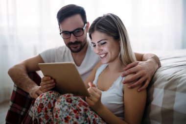 Genç mutlu çift yatak odasında dijital tablet kullanma