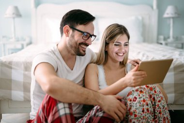 Genç mutlu çift yatak odasında dijital tablet kullanma