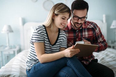Genç mutlu çift yatak odasında dijital tablet kullanma
