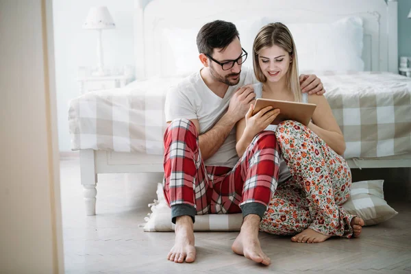 Genç mutlu çift yatak odasında dijital tablet kullanma
