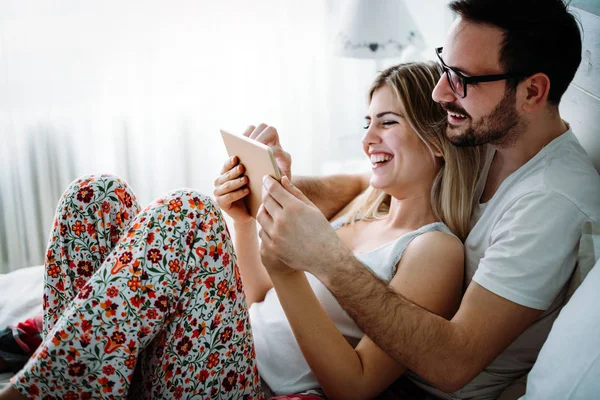 Genç mutlu çift yatak odasında dijital tablet kullanma