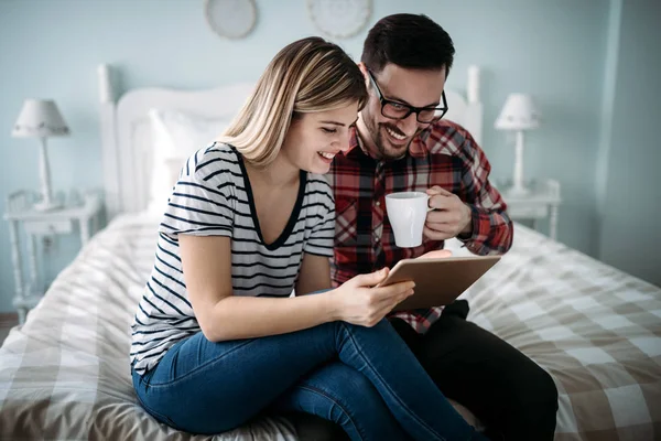 Genç mutlu çift yatak odasında dijital tablet kullanma