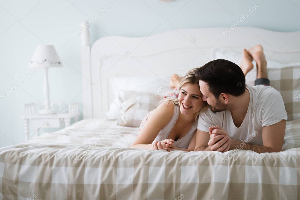 Portrait of young attractive loving couple in bedroom