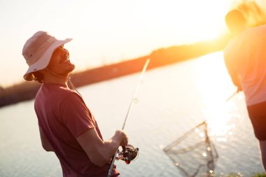 Men fishing in sunset  clipart