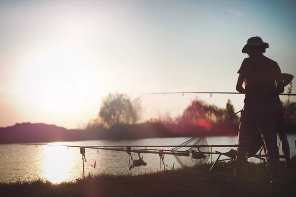 日落时在湖面钓鱼的年轻人 享受业余爱好和娱乐 — 图库照片