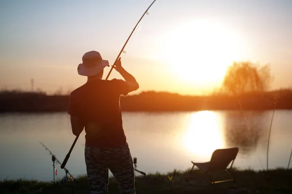 Молодой человек рыбачит в пруду и наслаждается хобби — стоковое фото