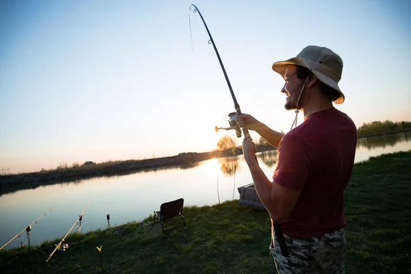 Ung man fiske vid dammen och njuter av hobby — Stockfoto