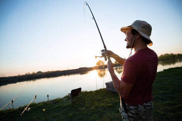 Young man fishing at pond and enjoying hobby