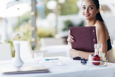 Güzel bir kadın restoranda menüden sipariş veriyor.