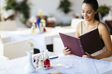 Güzel bir kadın restoranda menüden sipariş veriyor.