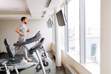 Spor salonunda koşu bandı üzerinde çalışan yakışıklı adam