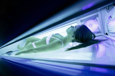 Güzel seksi esmer kadın solaryumda güneşlenme