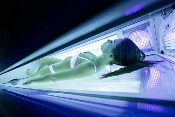 Güzel seksi esmer kadın solaryumda güneşlenme