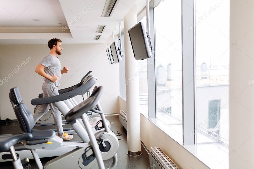 Handsome man running on treadmill in gym