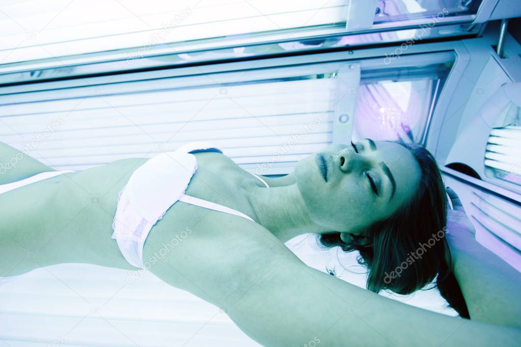 Beautiful woman lying in solarium and sunbathing