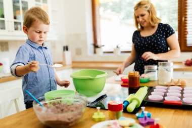Çocuk modern mutfakta annesine kurabiye yapması için yardım ediyor.