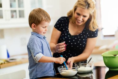 Çocuk modern mutfakta annesine kurabiye yapması için yardım ediyor.