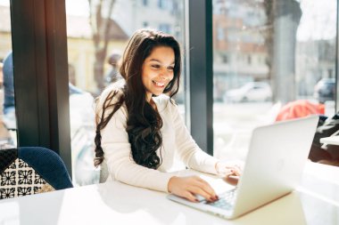 Güzel genç şirin esmer kafede dizüstü bilgisayar kullanarak