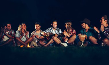 Arkadaşlar gece kamp ateşi yakın müzik keyfi