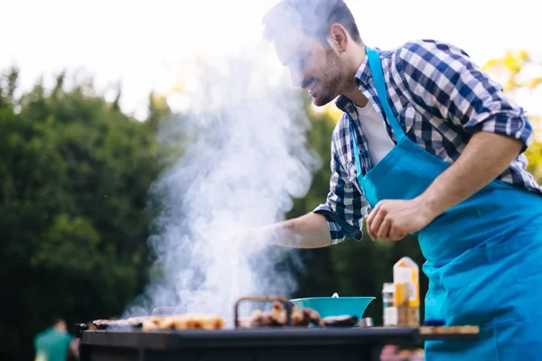 Kjekk Mann Som Lager Grillmat Utendørs Til Venner – stockfoto