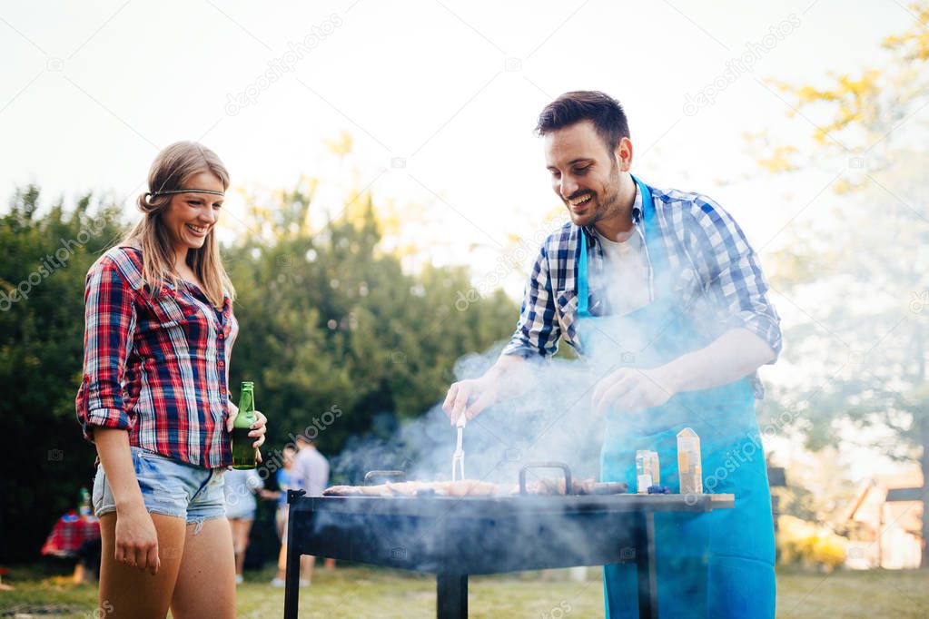 Happy students having barbecue on summer day in forest