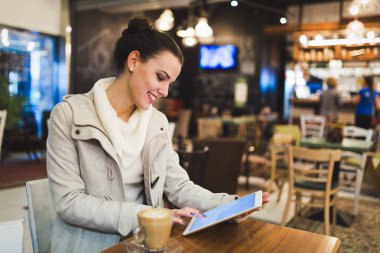 Kafede dijital tablet kullanarak çekici genç kadın