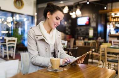 Kafede dijital tablet kullanarak çekici genç kadın