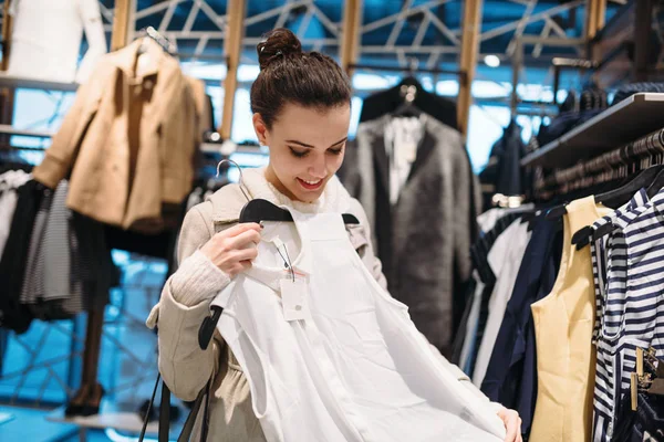 Young attractive woman buying clothes in shopping mall