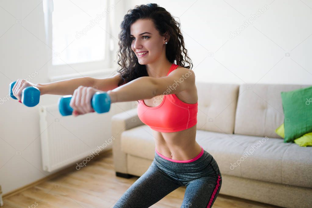 Young attractive sportswoman doing fitness exercises at home