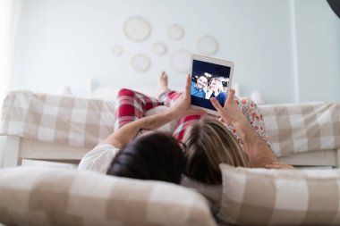 Birlikte kullanarak dijital tablet yatak odasında genç çekici çift