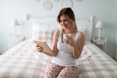 Genç güzel sarışın kadın yatak odasında dijital tablet kullanma