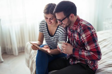 Mutlu genç çift yatak odasında dijital tablet kullanma