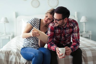 Mutlu genç çift yatak odasında dijital tablet kullanma