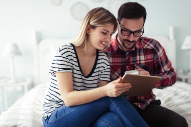 Mutlu genç çift yatak odasında dijital tablet kullanma