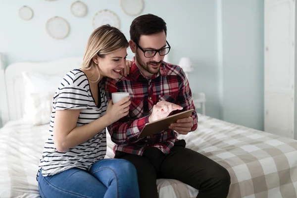 Happy young couple using digital tablet in bedroom