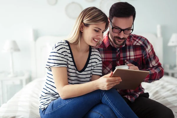 Mutlu genç çift yatak odasında dijital tablet kullanma