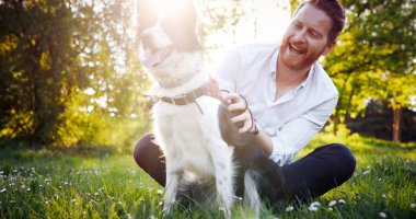 Adam köpeğini parkta kucaklayan