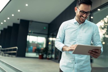 Mutlu ve kendine güvenen işadamı office merdivenlerde tablet kullanma