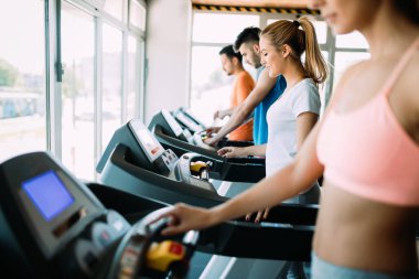 Spor salonundaki koşu bandındaki mutlu gençler