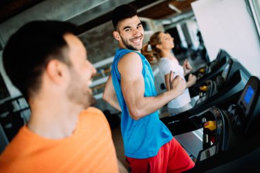 Spor salonundaki koşu bandındaki mutlu gençler