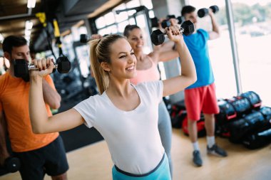 Atletik genç kadının spor salonunda dumbbells ile bir fitness egzersiz yapması