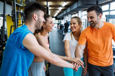 Egzersiz seansını tamamladıktan sonra fitness sınıfı beşlik çakıyor. Gülümseyen arkadaşlar başarılarını kutluyor.