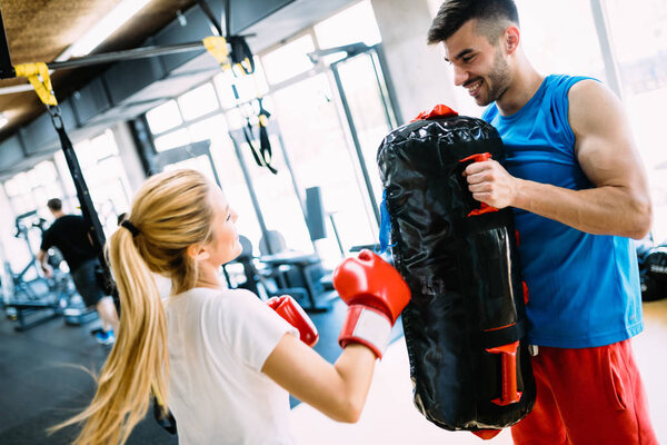 Boxing workout woman in fitness class ring. Man trainer holding sport mitts in gym