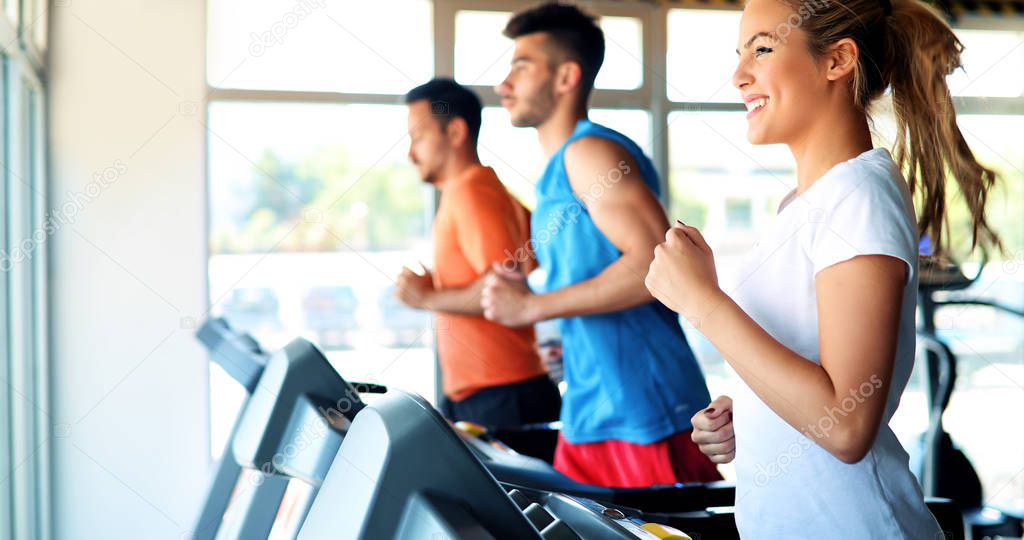 Group of friends exercising on treadmill machine in gym