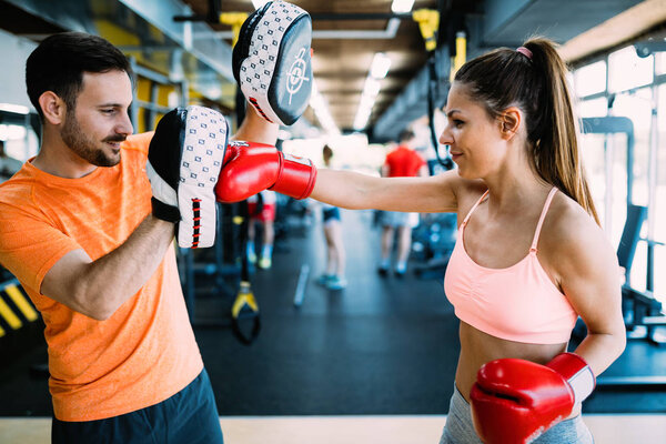 Portrait of beautiful woman wearing boxing gloves in gym