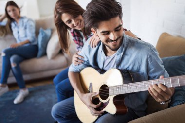 Genç yakışıklı adam güzel kız arkadaşı için gitar çalıyor.