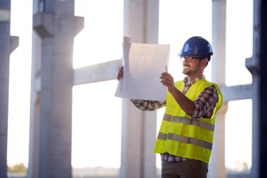 Mühendis bir mavi parmak tutan bir şantiyeye çalışıyor